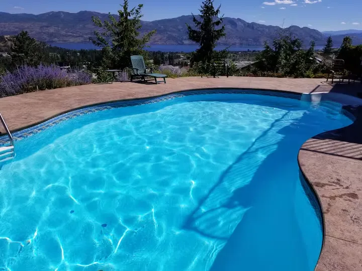 Sunlit swimming pool with lake and mountain views