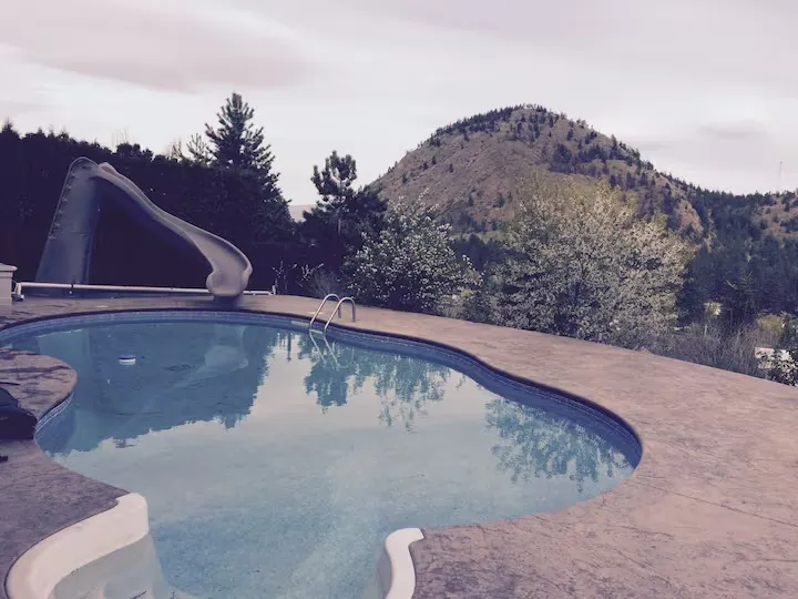Pool and water slide with hillside backdrop